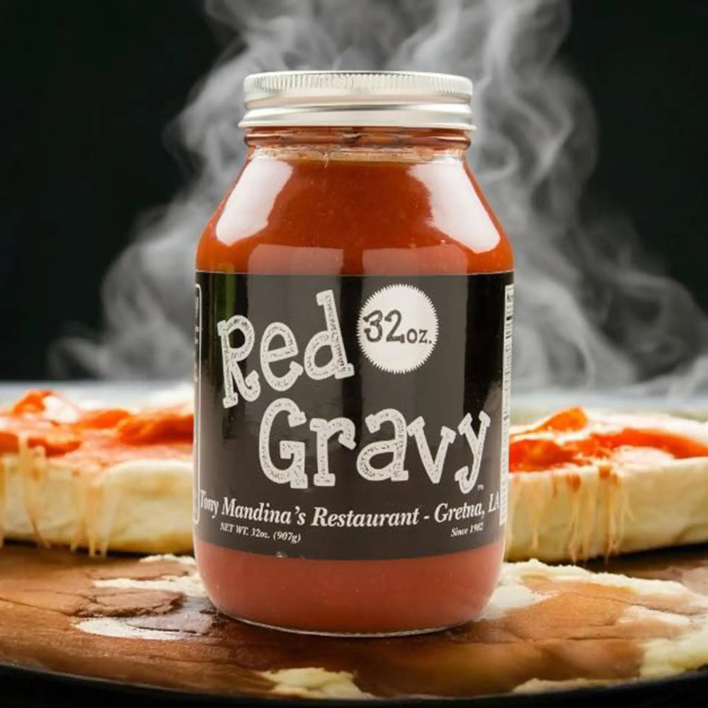 Jar of Tony Mandina's Red Gravy with steam rising, placed on a wooden surface with a blurred background.